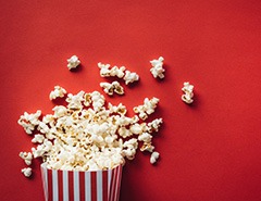 A bag of popcorn spilled out onto a red background