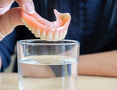 Patient placing dentures in a glass of water 