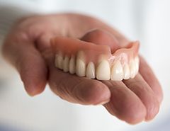 Hand holding a full denture