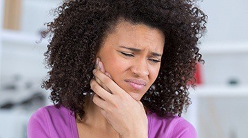 Woman holding cheek in pain