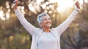 Woman outside smiling with arms outstretched in victory