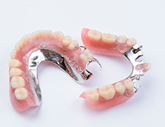 Set of partial dentures with metal clips on a white surface