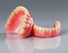 Complete set of dentures on reflective gray surface