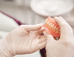 White-gloved hands holding full set of dentures 