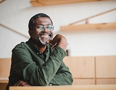 Man in green shirt with glasses sitting at table smiling