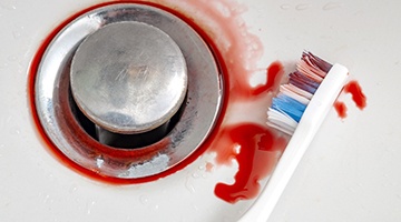 toothbrush in a sink with blood going down the drain