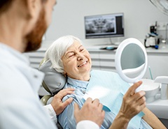patient admiring her smile after getting her dental implants restored 