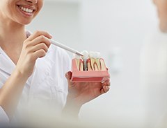 implant dentist showing a patient a model of a dental implant in the jaw 