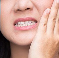 Close up of a person holding their cheek in pain