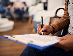 Woman filling out dental insurance form in lobby