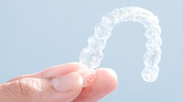 Hand holding Invisalign tray