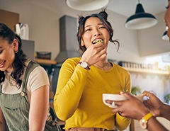 Group of friends smiling while enjoying meal in kitchen