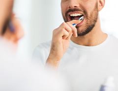 Man smiling while brushing his teeth