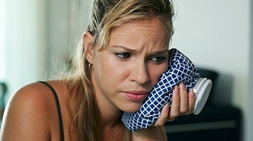 Woman holding ice pack to cheek