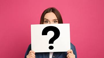 Woman holding a card with a question mark over her face