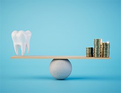 A balance beam scale holding a model tooth and stacks of coins