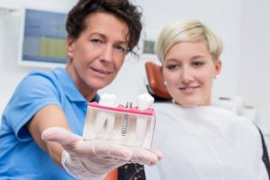 Dentist showing woman a dental implant model