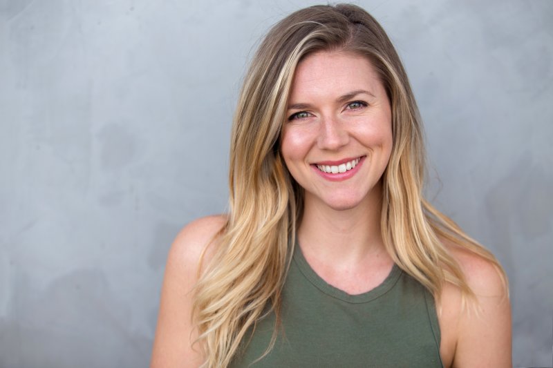 woman with blonde hair smiling on gray background