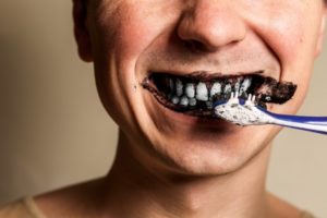 person brushing their teeth with activated charcoal