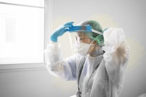 dentist in Newark wearing face shield, hair cap, mask, and surgical covering 