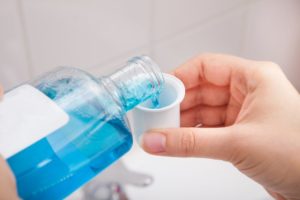 dentist in Newark pouring blue mouthwash into cup 