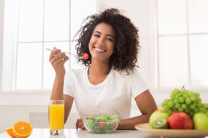 woman eating a salad to benefit her oral health 