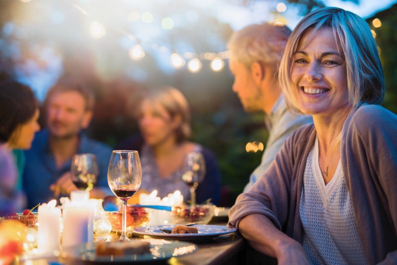 Woman with dental implants smiling at dinner table