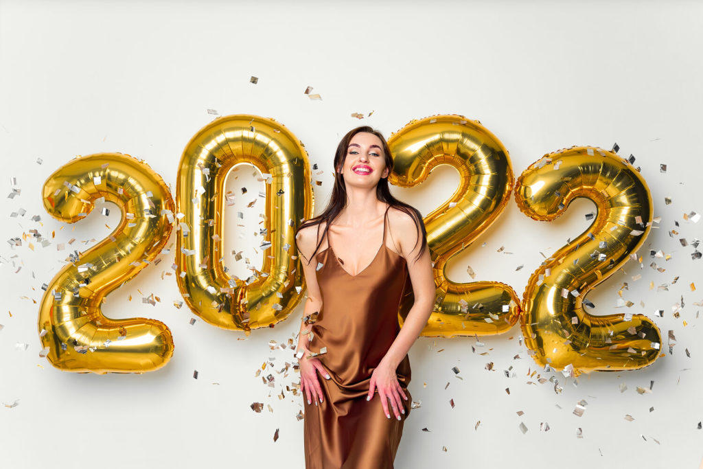 person smiling in front of 2022 New Year’s balloons
