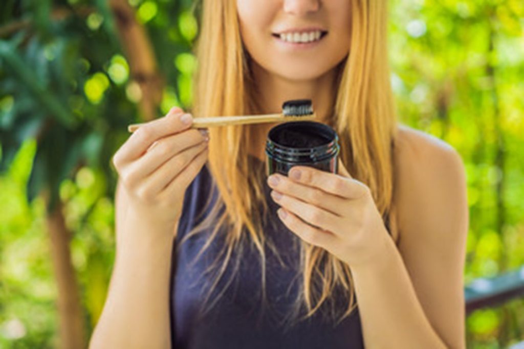 Woman using activated charcoal on her toothbrush.