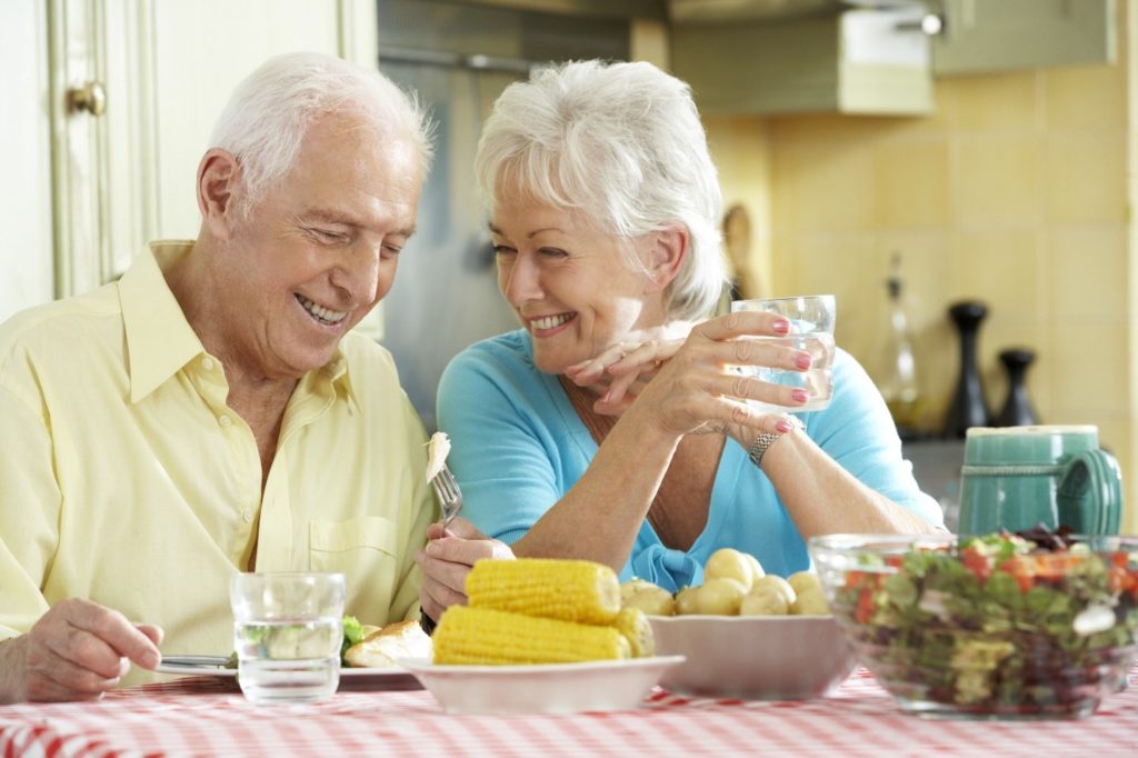 Older couple enjoying summertime foods with dental implants.