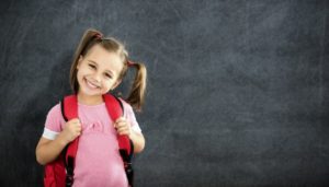 little girl with pigtails smiling after seeing children’s dentist in Newark 