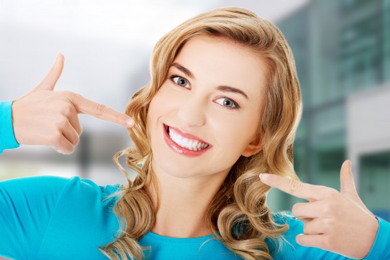 A woman pointing to her beautiful smile 