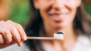 Woman holding toothbrush with charcoal toothpaste
