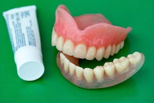 Tube of denture adhesive next to set of dentures.